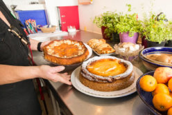 Ulrike Grambow in der Stationsküche; sie hält zwei Platten mit Kuchen.