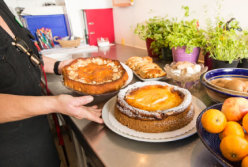 Ulrike Grambow in der Stationsküche; sie hält zwei Platten mit Kuchen.