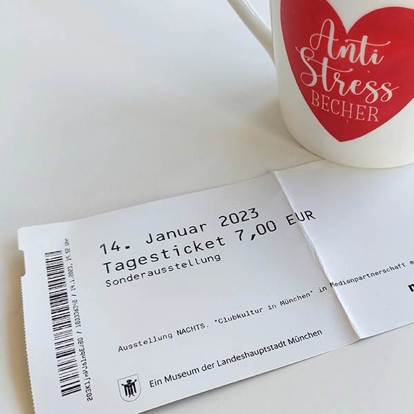 Eine Museums-Eintrittskarte unter einer Tasse mit Herz-Aufdruck.