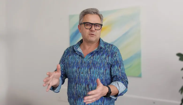 Josef Hell im Interview. Er spricht und hebt die Hände zu einer Erklärung.