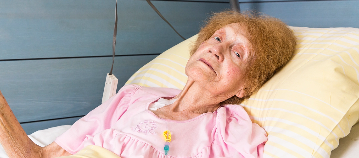 Frau W. liegt im Krankenbett und blickt in die Kamera