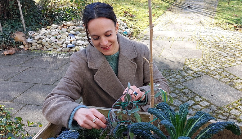 Anna vor einem kleinen Hochbeet mit Kräutern.